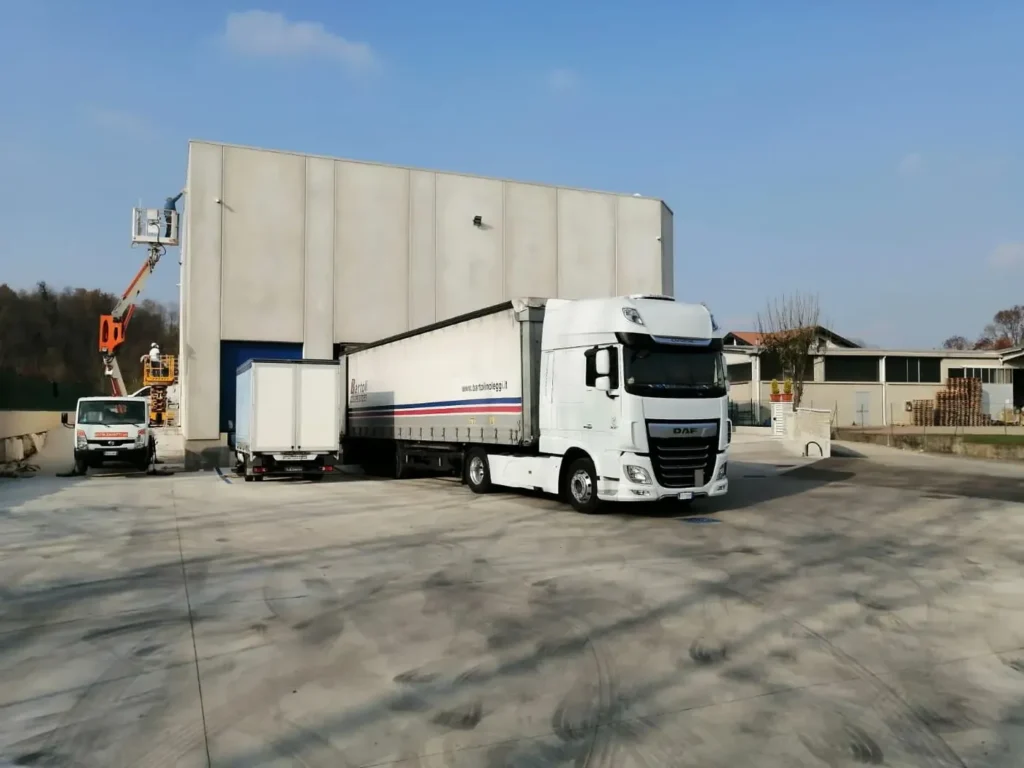 Camion bianco con semirimorchio vicino a un magazzino nel piazzale