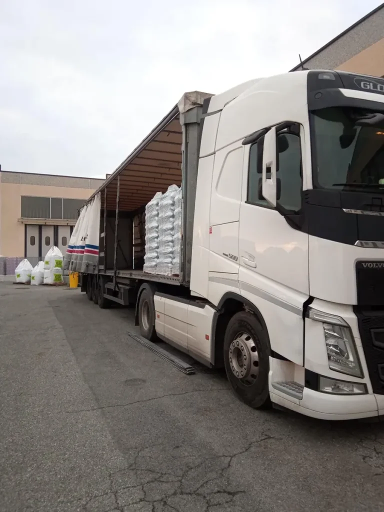 Fianco di un camion bianco con tendone laterale aperto e merce a bordo