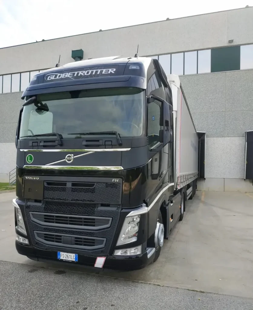Cabina di un camion Volvo nero davanti a un capannone industriale